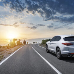 car on road with sun in distance - deposit photos